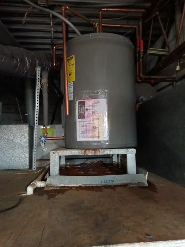 Newly installed residential water heater with copper supply lines and a warranty tag still attached.